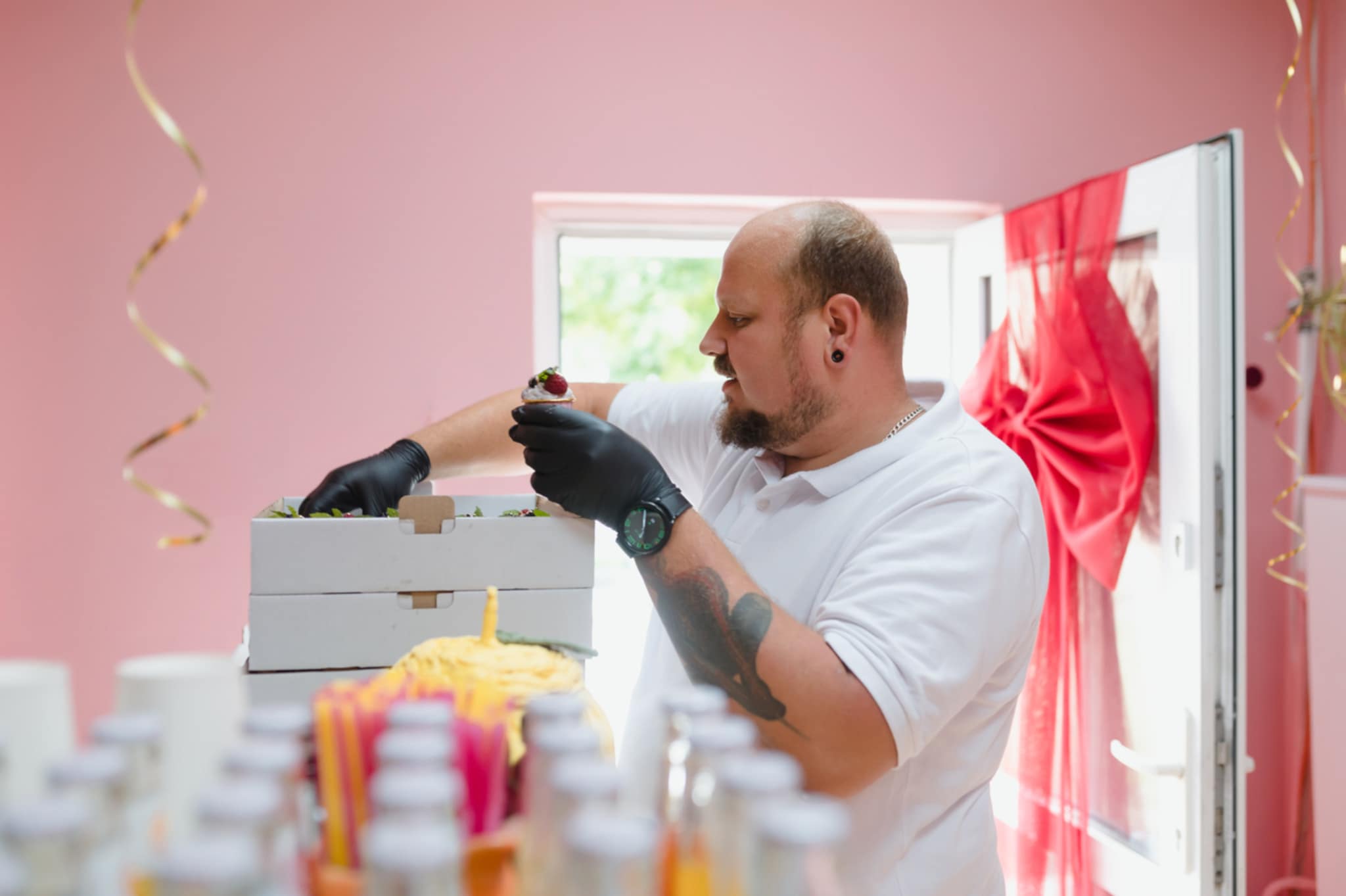 Cukiernik Artur Marek dekorujący deser przy stole w pracowni cukierniczej